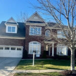 Exterior view of a two-story house with a prominent front-facing garage, lush green lawn, and a 'Coming Soon' sign in the yard, representing new houses for sale in Rock Hill SC.