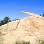 Adventurous hiker standing confidently on Potato Chip Rock, a thin, wafer-like rock formation in Poway, California, showcasing the thrill of the hike.