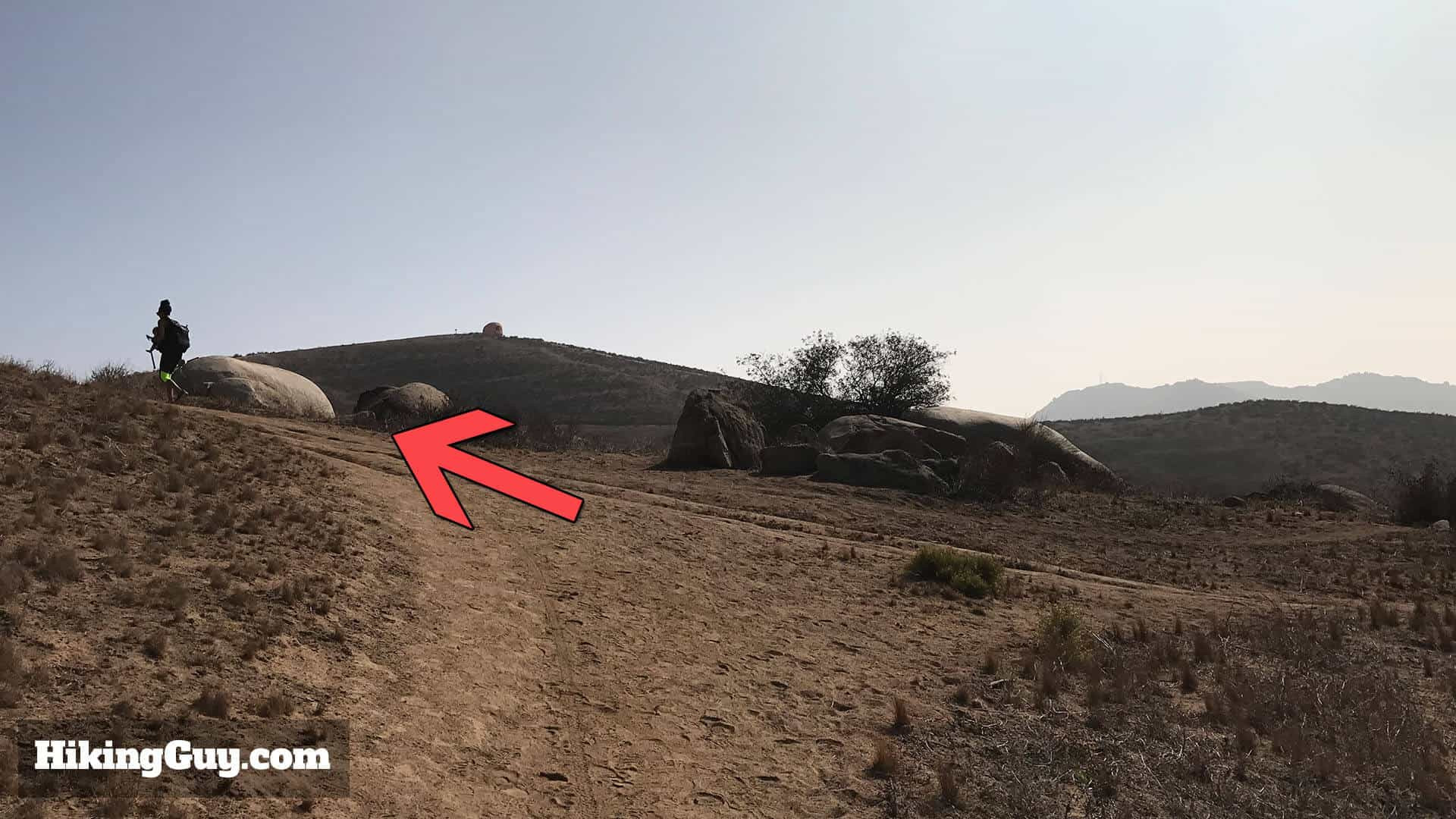 Pumpkin Rock Visible in the Distance on Trail: At around 0.3 miles, head left towards Pumpkin Rock, now visible in the background, guiding your path.