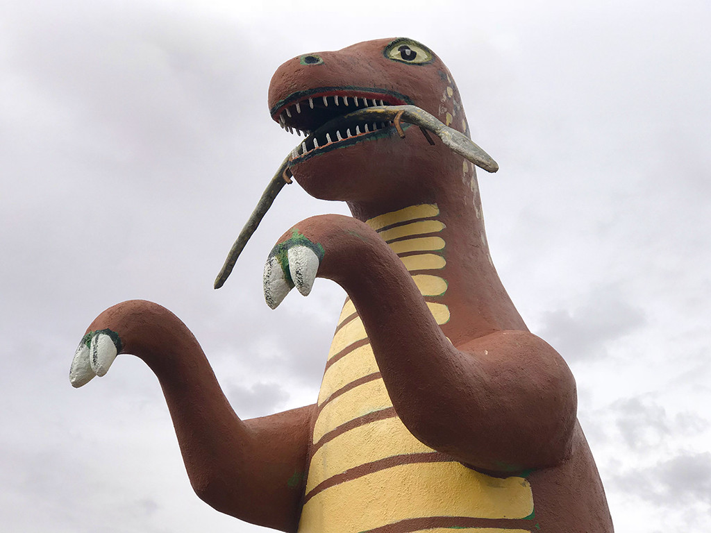 A wide shot of the Rainbow Rock Shop dinosaurs lined up along the roadside, showcasing their size and variety