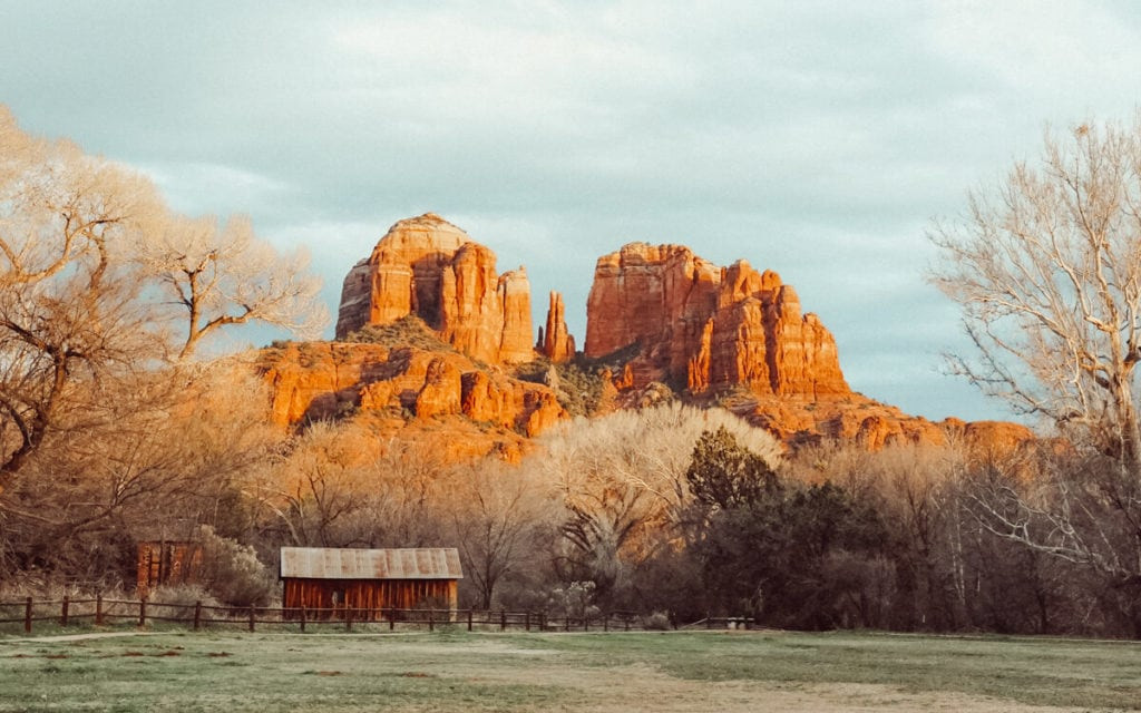 A panoramic sunset view of Red Rock Crossing Vortex in Sedona, Arizona, showcasing the expansive red rock landscape under a colorful sky.