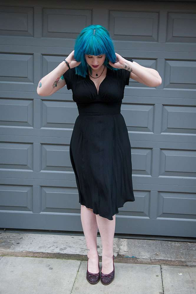 Kat Forsyth in a black 1940s dress paired with a metallic clutch