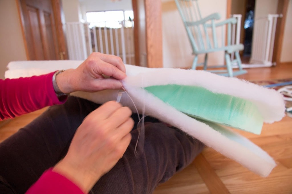 Securing batting around foam cushions for a rocking chair, demonstrating how to encase the foam with batting