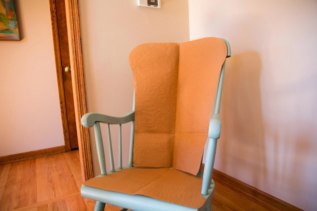 Close-up of a paper template being used to outline the shape for a rocking chair cushion, demonstrating template creation