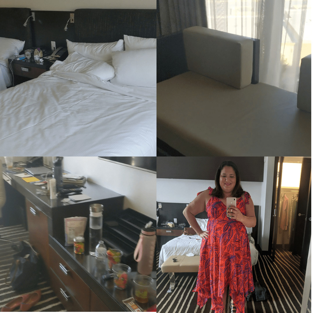 The bed in the Red Rocks Resort room, a sofa by the large window, the dresser and desk area in the room, and an image of a woman in the mirror showing the bed and closet