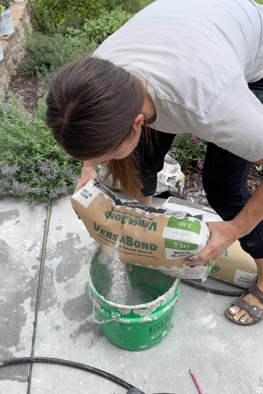 Close-up of dry mortar mix being poured into a mixing bucket.