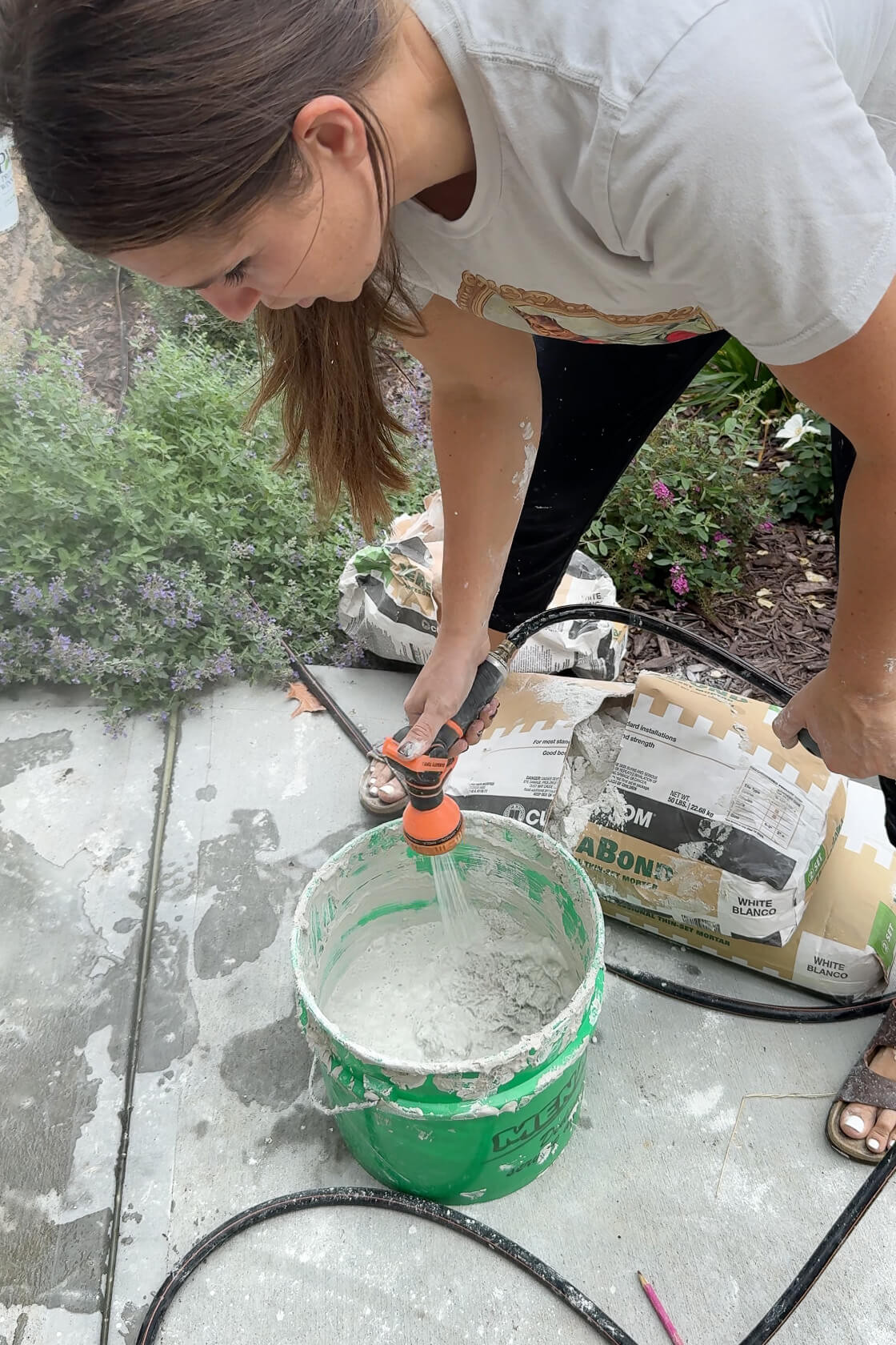 Using a drill with a paddle attachment to mix mortar in a bucket.