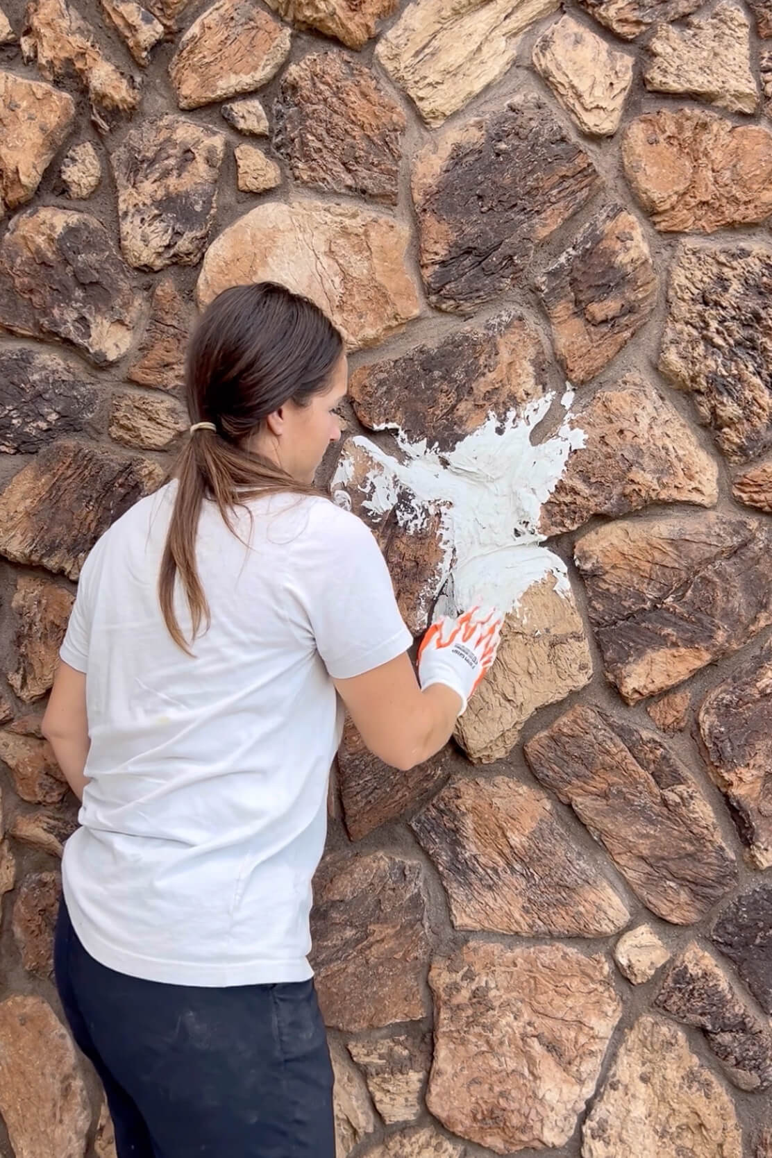 Close-up of mortar being applied and spread onto the rock siding.