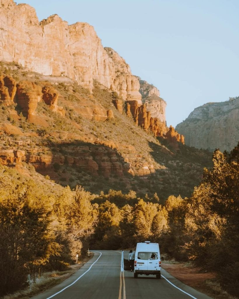 A scenic drive along Boynton Pass Road in Sedona at sunrise, with a campervan heading towards the rising sun.