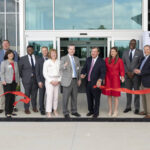 UAMS Chancellor Cam Patterson, Gov. Sarah Huckabee Sanders, and Dr. C. Lowry Barnes cut the ribbon at the Orthopaedic & Spine Hospital opening, surrounded by hospital and city officials.