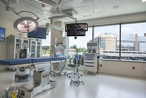 A spacious operating room inside the UAMS Orthopaedic &amp; Spine Hospital, featuring advanced surgical equipment and a view of the main hospital.