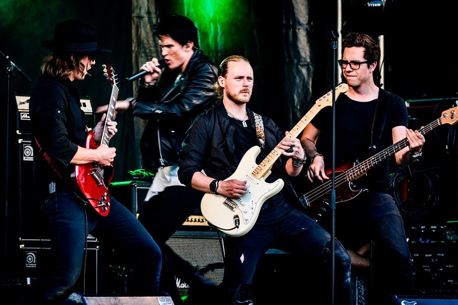 Classic rock concert featuring a band performing on stage with a crowd in the background