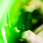 Robert Lowndes holding up a moon rock in green lighting.