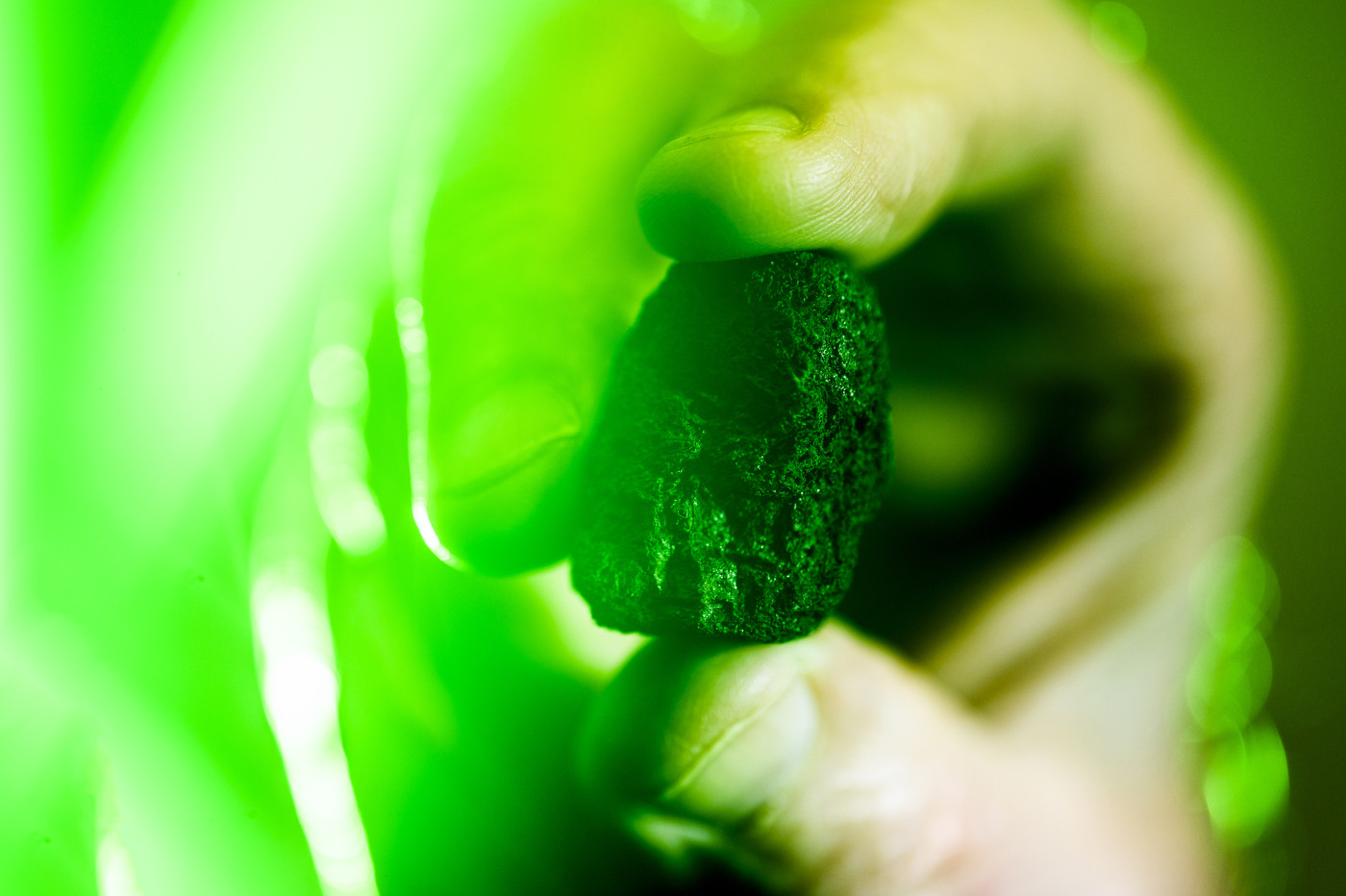 Robert Lowndes holding up a moon rock in green lighting.