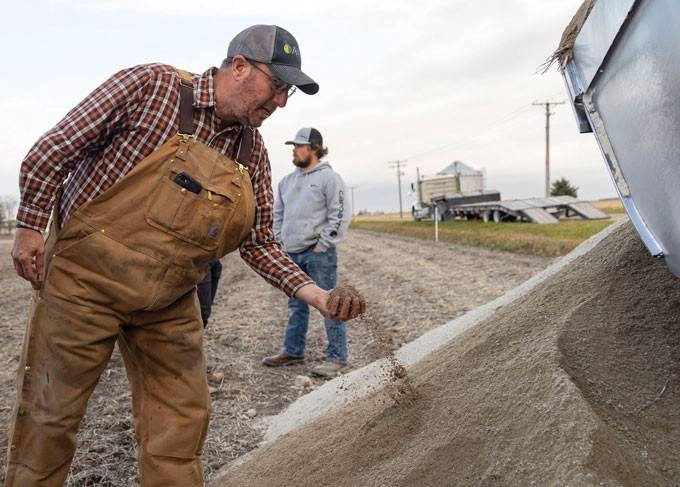 Farmer inspecting rock dust after application to soybean field