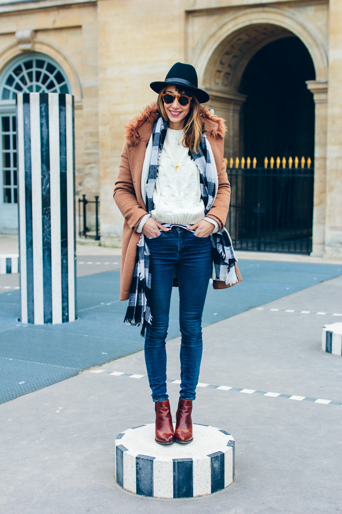 Woman layering an oversized sweater with a denim jacket and jeans, creating a stylish casual outfit