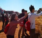Tourists taking photos from the base walk area at Uluru, showcasing the beautiful landscape and cultural significance