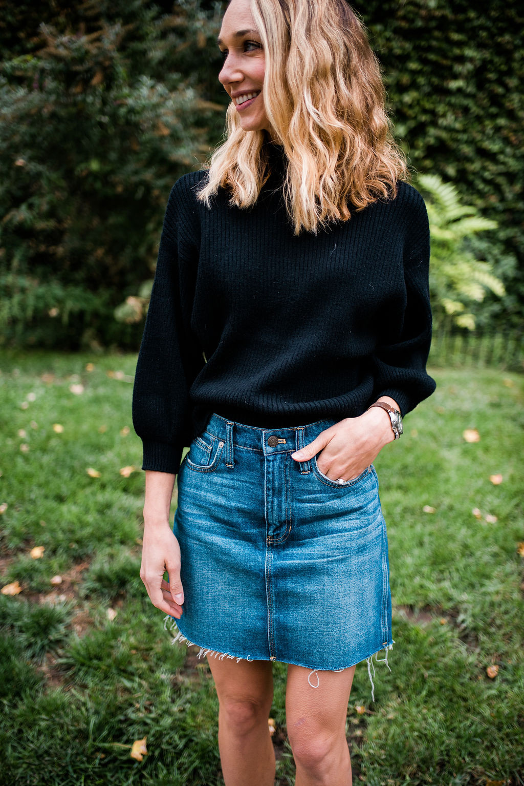 Woman pairing a black oversized sweater with a denim skirt, showcasing a stylish and balanced look
