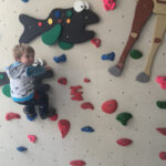 Child is enjoying the climbing, she is raising hands up and reaching next step