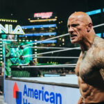 Dwayne The Rock Johnson stands tall amidst a cheering crowd, showcasing his charismatic smile and muscular physique, embodying his electrifying presence in sports entertainment