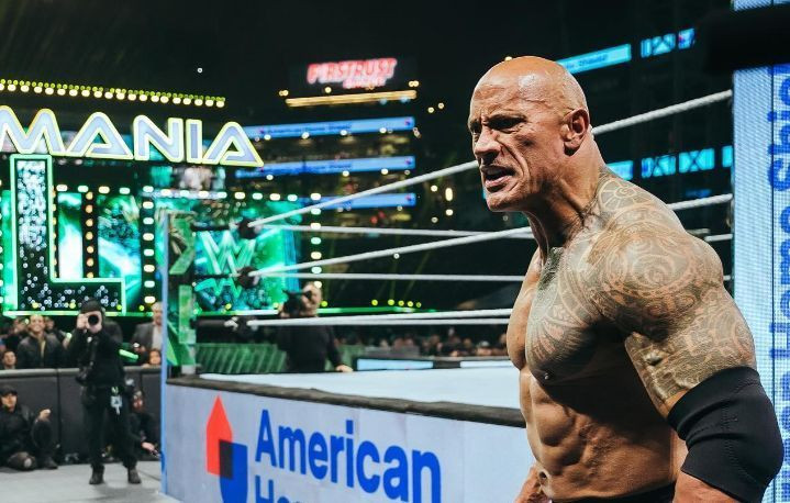 Dwayne The Rock Johnson stands tall amidst a cheering crowd, showcasing his charismatic smile and muscular physique, embodying his electrifying presence in sports entertainment
