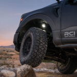 Rock lights illuminating the underside of an F-150, enhancing visibility for rock crawling