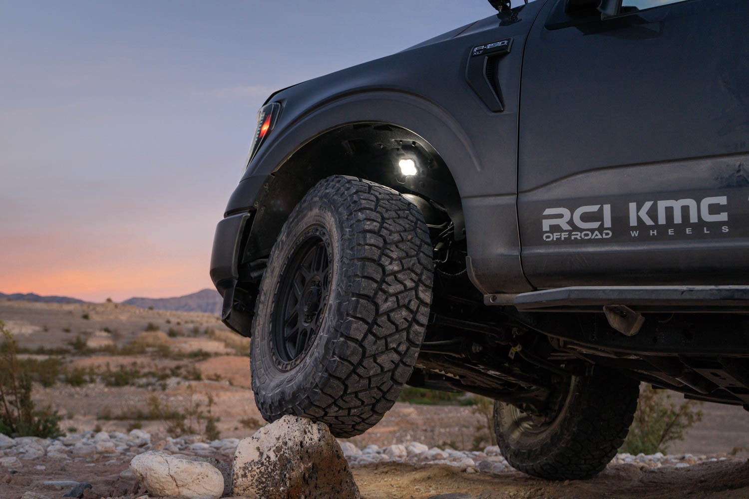Rock lights illuminating the underside of an F-150, enhancing visibility for rock crawling