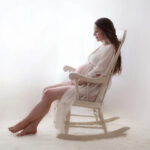 Pregnant woman relaxing in a wooden rocking chair in a sunny nursery, fostering prenatal well-being