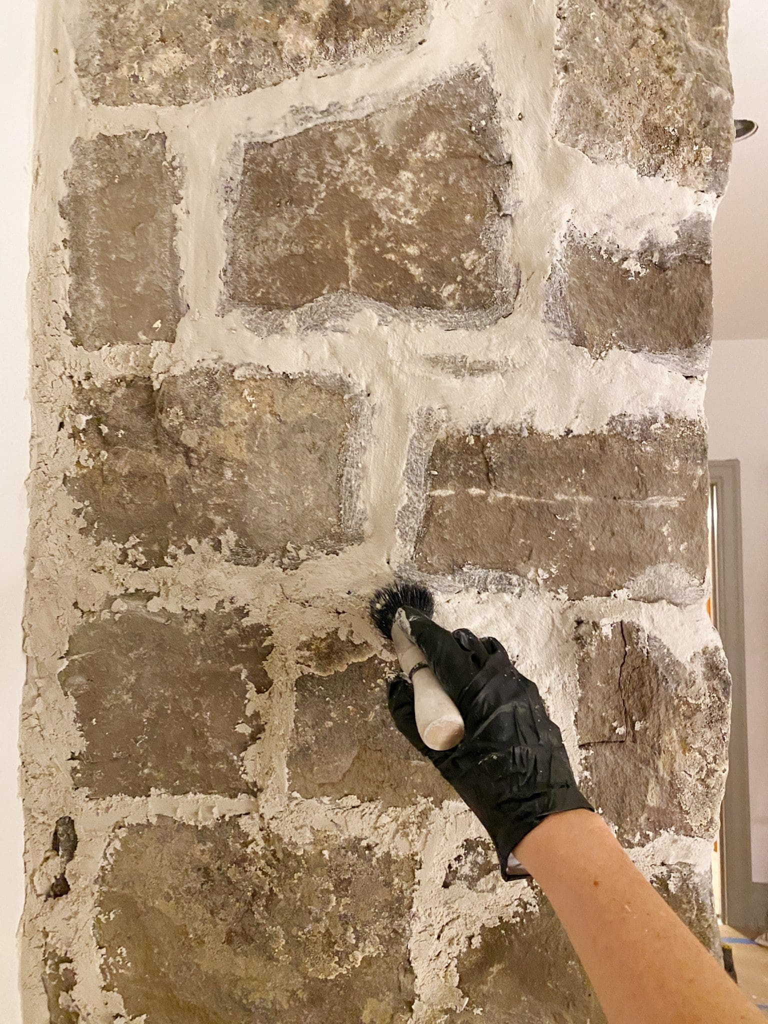 Cleaning a rock fireplace wall with a scrubby sponge