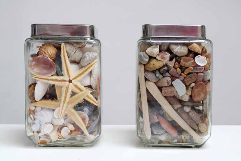 Colorful rocks and gemstones arranged in glass jars on a windowsill
