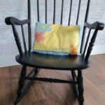 Old wooden rocking chair surrounded by lush greenery in a garden setting, showcasing a rustic and charming decor idea