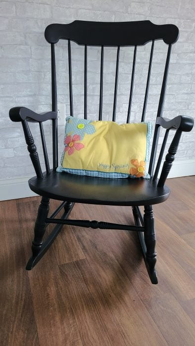 Old wooden rocking chair surrounded by lush greenery in a garden setting, showcasing a rustic and charming decor idea