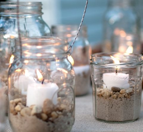 A candle jar filled with gemstones, soil, and a lit candle
