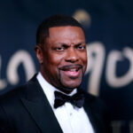 Chris Tucker wears a dark suit and furrows his brow of camera