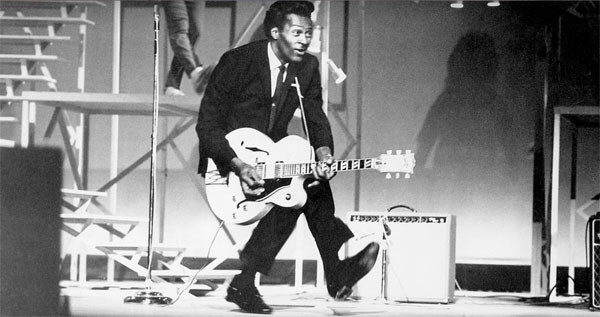 Chuck Berry playing guitar doing his famous duck walk, his style of play is studied by rock and roll guitarist to this day