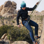 Climber wearing jeans outdoors for rock climbing, showcasing denim's durability