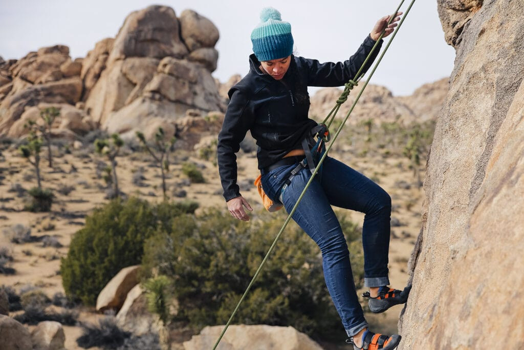 Climber wearing jeans outdoors for rock climbing, showcasing denim's durability