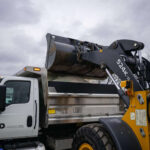 Commercial maintenance crew filling snow removal truck with rock salt