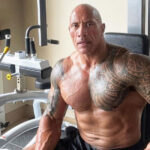 Dwayne Johnson bench pressing weights in his gym