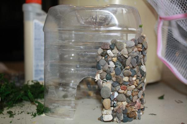Applying stones to create a rock fairy house