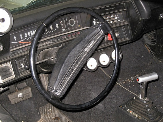 A close-up of the 1971 Chevrolet Chevelle used in the movie Faster, showcasing its flat black paint job and white racing stripes.