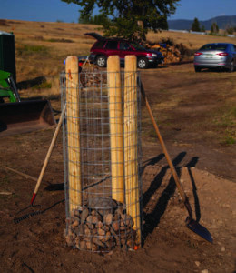 Filling the rock fence post cage with various stones, showing the construction process of adding structural integrity