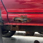 Front rust hole on rocker panel of vehicle