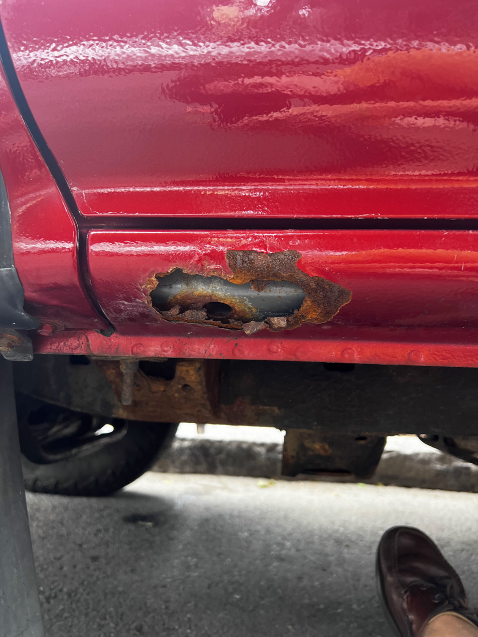 Front rust hole on rocker panel of vehicle