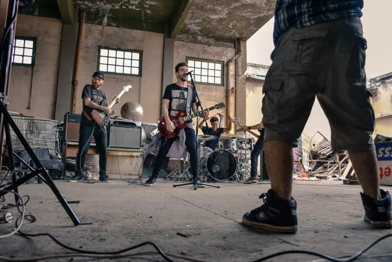 Rock band members collaborating on songwriting in a rehearsal space, showcasing teamwork and creativity
