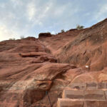 Hikers navigating a rock scrambling section on Cathedral Rock Trail, demonstrating the need for agility and balance