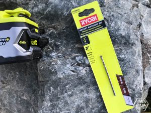 Using a hammer drill and masonry bit to create holes in a rock for metal sign attachment