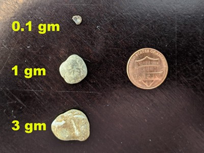 Pebbles next to a penny for scale, illustrating their individual weights
