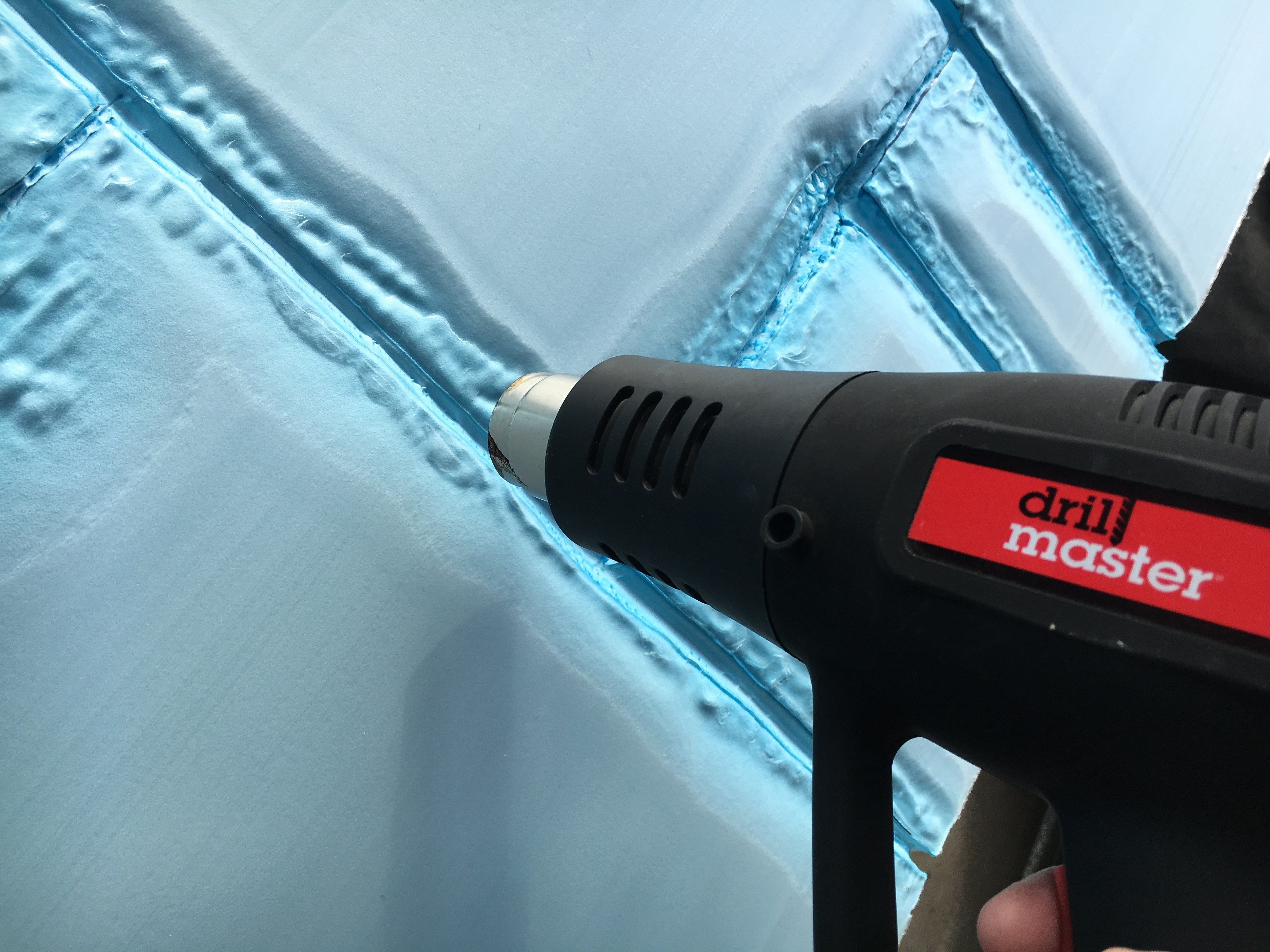 Installing painted foam stone sheets on a wall using adhesive and screws to create a faux rock wall.
