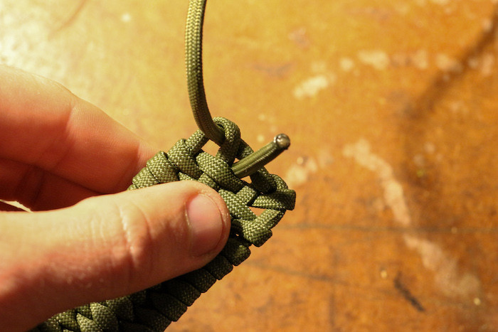 End your weave by passing the paracord through the hole in the center of the pouch.